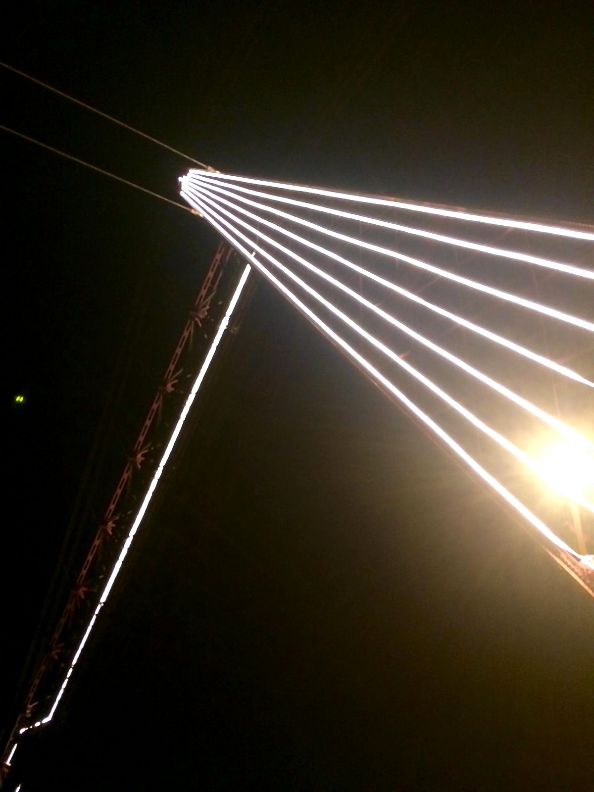 Líneas de LED convergiendo en lo alto de la torre del puente contra el cielo nocturno